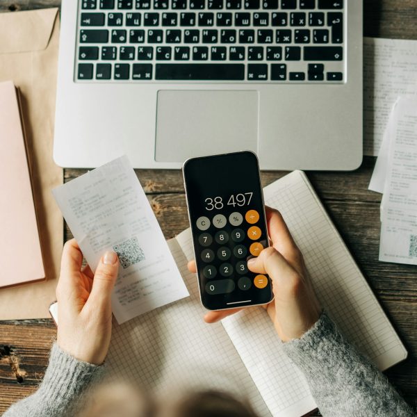 Close-up of a woman counting bookkeeping on a calculator on a phone screen.